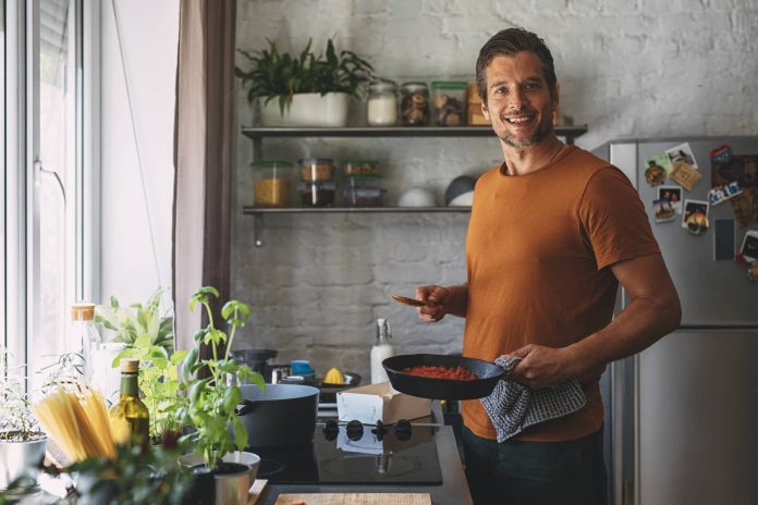 Handsome Young Caucasian Man Making Sauce in a Kitchen